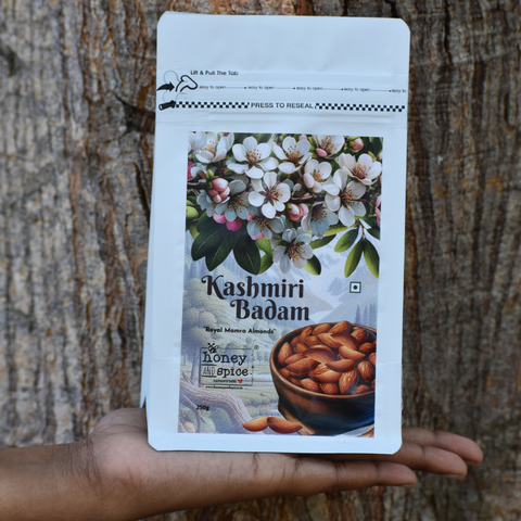 Kashmiri Badam 250g pack held in hand – Royal Mamra almonds with floral design and tree bark