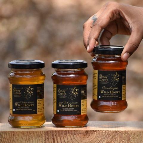 Three Jars of wild honey including South Indian and Himalayan varieties, displayed on a wooden surface.
