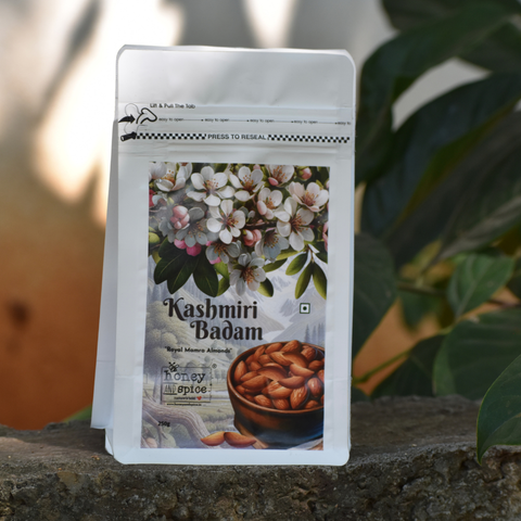 Kashmiri Badam front pack on outdoor stone ledge – Premium almonds with blooming flower art.