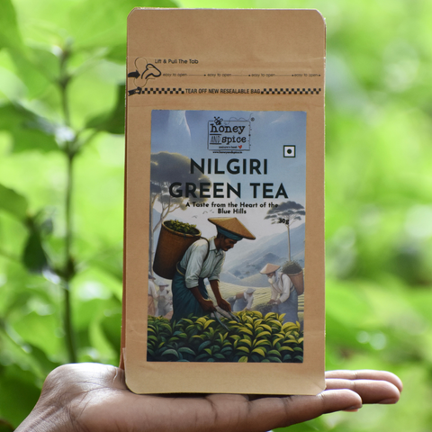 Nilgiri Green Tea 30g pouch held in hand with lush tea garden background.