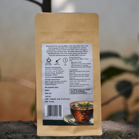 Back view of Nilgiri Green Tea pouch with brewing guide – Shot outdoors on stone with soft natural backdrop.