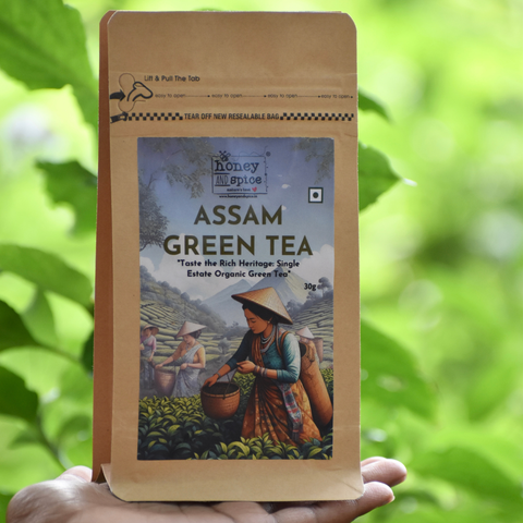 Assam Green Tea pouch held in hand with green foliage background