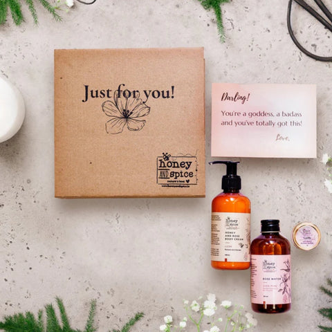 Self-care gift box with body cream, body wash, and lip balm on a floral background