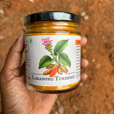Lakadong Turmeric jar held in hand with an earthy background, highlighting its organic authenticity.
