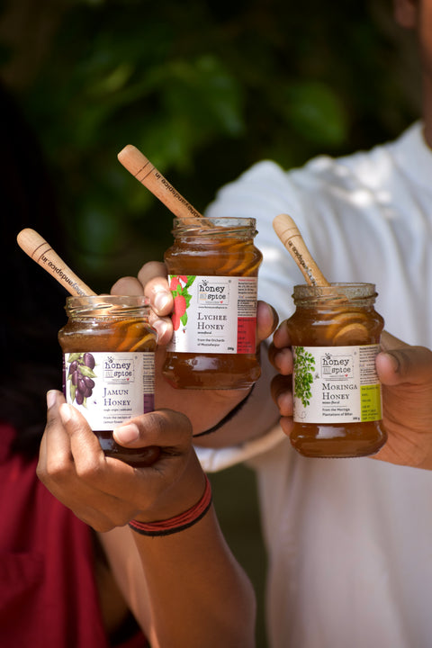 Group holding raw honey jars – natural honey varieties enjoyed together outdoors