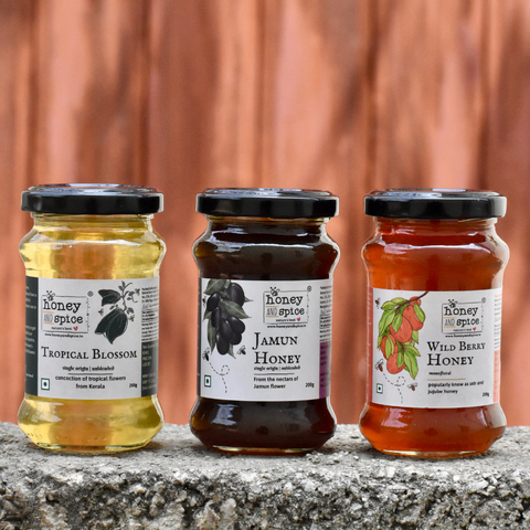 Three honey jars - Tropical Blossom, Jamun, and Wild Berry varieties, natural and pure.